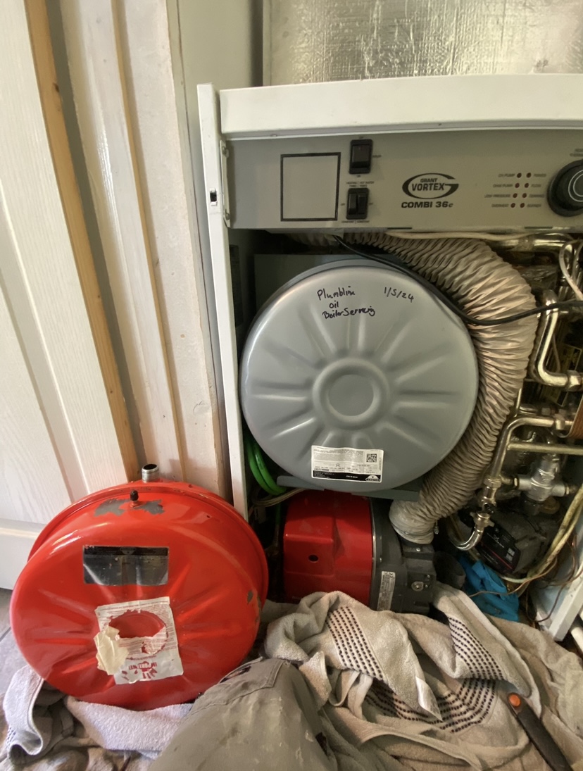 An open Grant oil combi boiler with its red expansion vessel, mid service