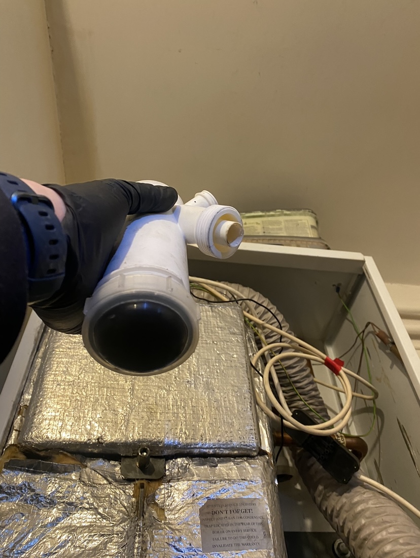 A boiler part held over an open oil boiler during a service