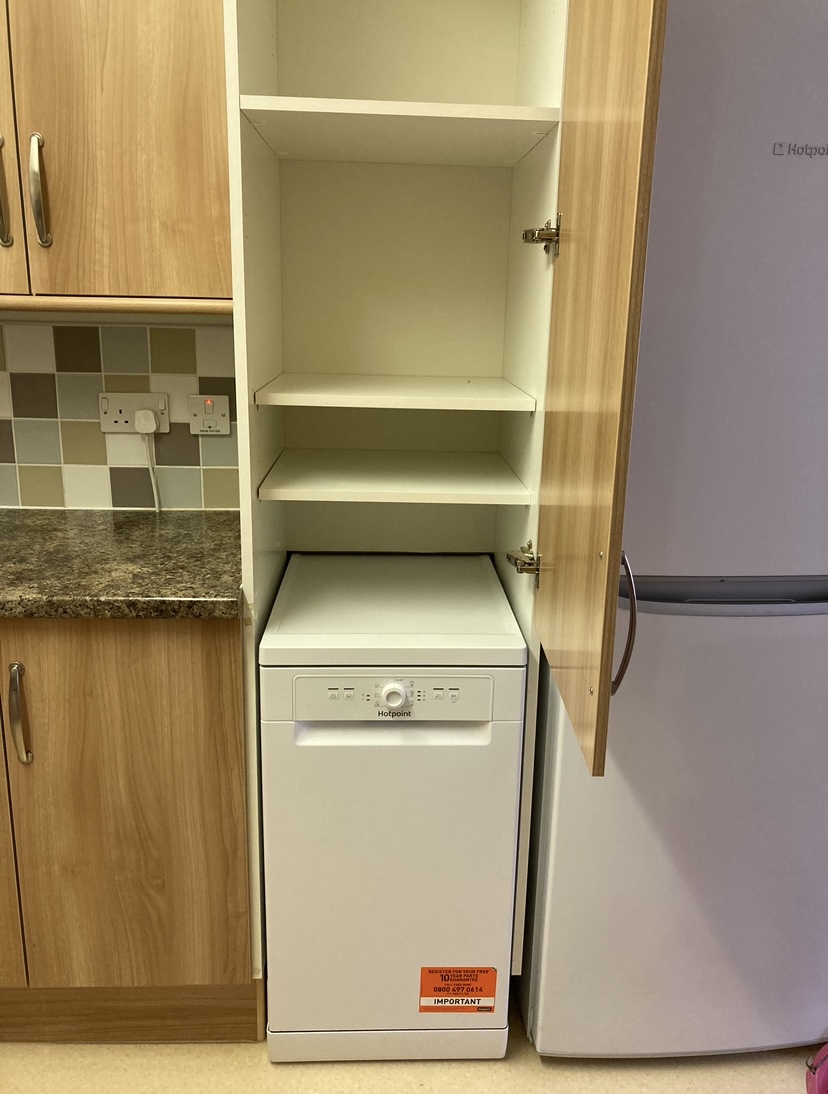 A kitchen cupboard and appliance space with a service label on the appliance